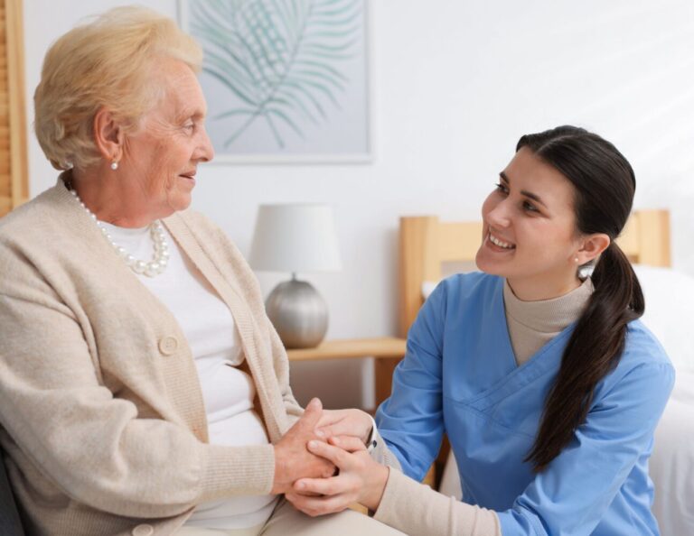 Une infirmière souriante tient la main d'une dame âgée
